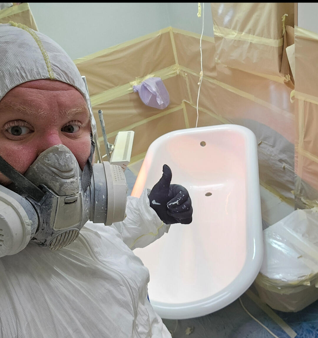 photo of glossy baths owner photo of glossy baths re-enamelling owner Seamus with a thumbs up, in ppe, in a room full of masking up and a completed bath in Solihull